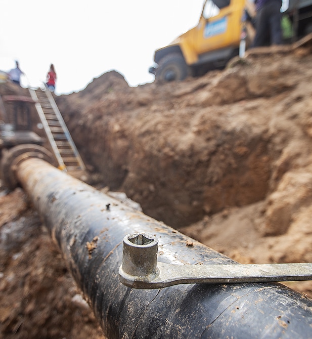 Réparation de Canalisation : Chantier de Travaux Publics Douille de serrage sur une canalisation d'eau noire dans une tranchée de chantier de travaux publics.